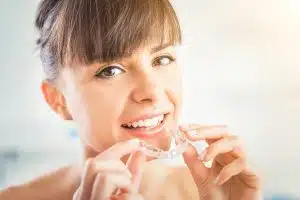 woman holding her clear aligners while smiling