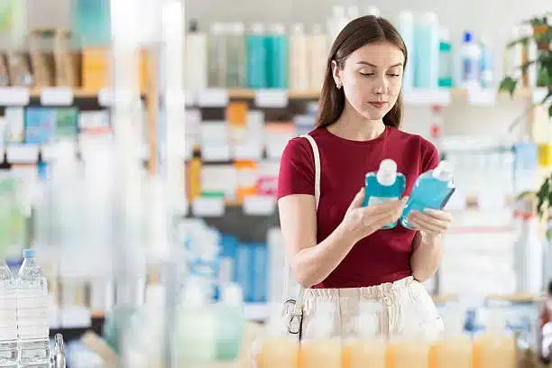 Patient comparing therapeutic mouthwash bottles in a pharmacy aisle